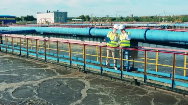 Dos especialistas masculinos discutiendo en una planta de tratamiento de aguas residuales — Vídeos de Stock