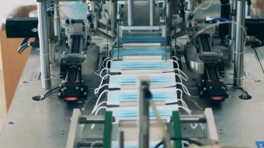 Tıbbi maske üretim fabrikasında kulak ilmiği ekleme makinesi çalışıyor.