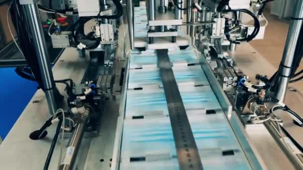 Produktion av medicinska kläder. Öronöglor för ansiktsmask som sätts fast av en maskin vid en fabrik för tillverkning av medicinska masker — Stockvideo