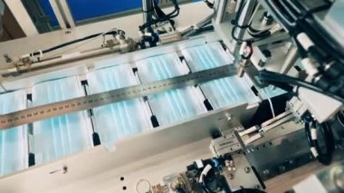 Yüz maskeleri modern bir yüz maskesi fabrikasında konveyör boyunca hareket ediyor.