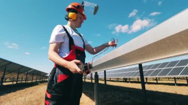 Güneş enerjisi mühendisi özel bir alet kullanarak güneş panellerini güneş çiftliğinde koruyor.