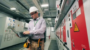 Elektrikçi bilgisayarını kullanarak güç istasyonunu izliyor. Güneş enerjisi kavramı.
