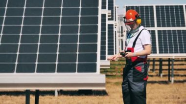 Güneş paneli teknisyeni çoklu metre kullanarak güneş panellerini inceliyor