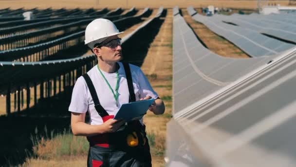 Pracovník solárního průmyslu kontrolující solární panely na solární farmě — Stock video
