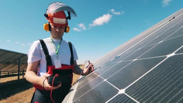 Специалист по солнечной энергии контролирует солнечные батареи с помощью мультиметра. Альтернативный, зеленый энергетик. — стоковое видео