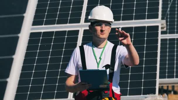 Especialista em energia solar examinando painéis solares com seu tablet em um parque solar. Conceito de energia solar. — Vídeo de Stock