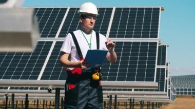 Güneş paneli teknisyeni güneş çiftliğinde çalışıyor.