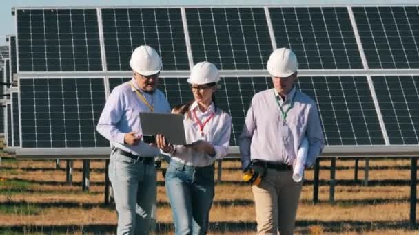 Команда специалистов по солнечным энергетическим системам, гуляющих в солнечном парке — стоковое видео