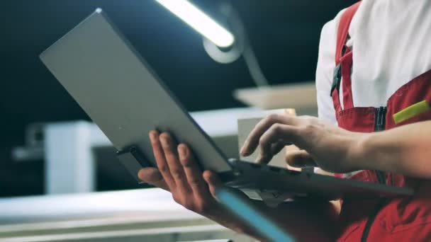 Closeup of engineer hands typing on laptop at metal factory — Stock Video