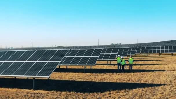 Tre ingegneri dell'energia solare che ispezionano un parco solare. Ingegneri professionisti discutono progetto innovativo. — Video Stock