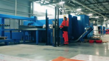 Fabrikanın içi. Operatör bir endüstriyel kesim makinesini yönetiyor.