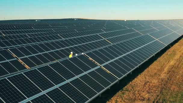 大規模な太陽光発電所での3人の太陽エネルギー技術者の空中撮影 — ストック動画