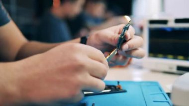 Servis teknisyeni çipteki aletleri inceliyor. Eller yukarı..