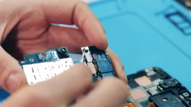 Tamirci mikroçipi cımbızla parçalara ayırıyor. Eller yukarı..