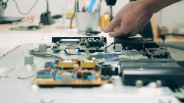 Teknisyen monitör ekranını elektrikli tornavidayla parçalıyor.