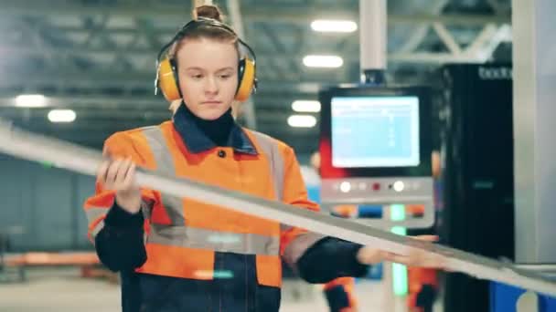 Dělnice v průmyslu kontroluje kovovou tyč. — Stock video