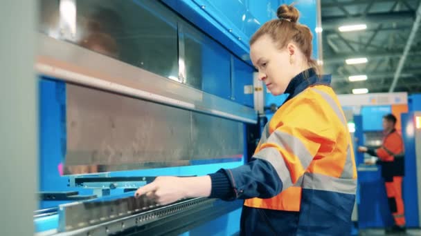 Γυναίκα εργαζόμενος χρησιμοποιεί μια μηχανή εργοστάσιο για να λυγίσει ένα μεταλλικό κομμάτι — Αρχείο Βίντεο