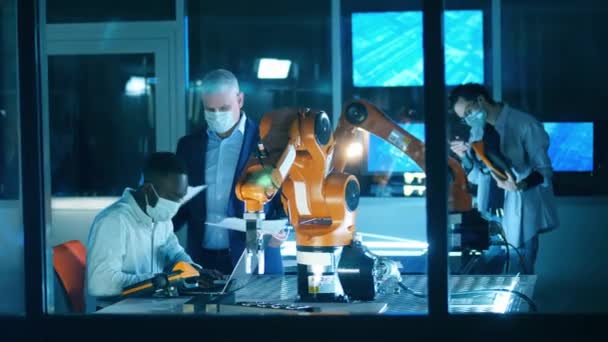 Forschergruppe mit Mundschutz untersucht Robotergeräte — Stockvideo