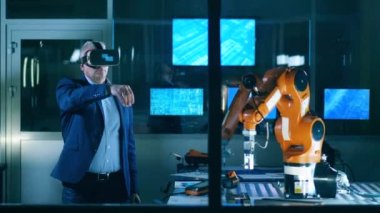 Erkek araştırmacı VR gözlük kullanırken bir robotu kontrol ediyor