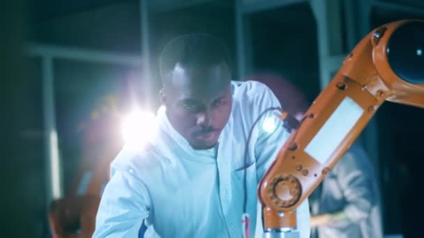 Afrikaanse onderzoeker onderzoekt een robotmechanisme in beweging — Stockvideo