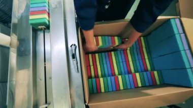 Fabrika işçisi temizlik süngerlerini bir kutudan taşıyıcıya yüklüyor.