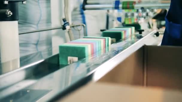 Factory worker loading scrub sponges onto a conveyor at a factory — Stock videók