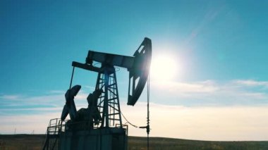 Yalnız bir petrol sahası pompası. Açık gökyüzüne karşı ağır çekim.