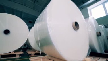 Plastik fabrikası deposunda büyük makaralı polimer film.