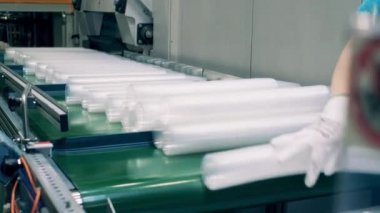 Eldiven giymiş, plastik bardak destelerini plastik poşetlere dolduran kadın işçi.