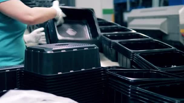 Рабочие складывают черные пластиковые контейнеры с производственной линии — стоковое видео