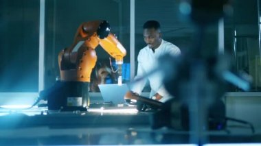 Afrikalı bir adam bir robotu kontrol etmek için dizüstü bilgisayar kullanıyor.