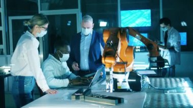 Yüz maskeli mühendisler bir robotik cihaz araştırıyor.