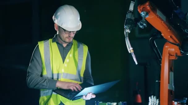 Male engineer is managing a robotic device with the laptop — Stock Video