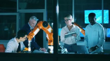 Bir grup mühendis otomatik bir cihazı iş başında izliyorlar.