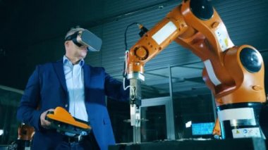 VR gözlüklü erkek mühendis bir robotik cihaz kullanıyor.