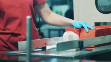 Bitki işçisi konveyörden kağıt mendil alıyor.