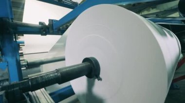 Büyük bir kağıt rulosu olan fabrika makinesi yaralanıyor.