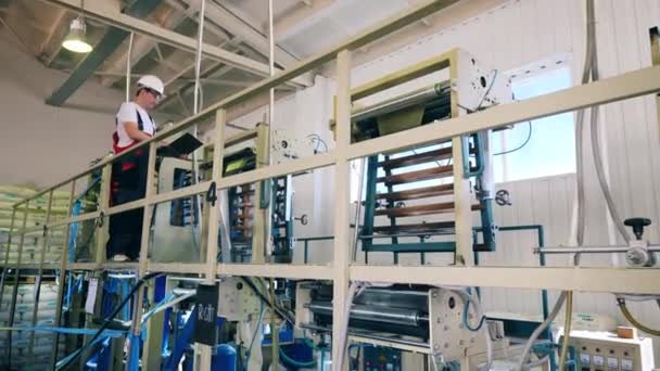 Mannelijke fabrieksarbeider inspecteert een polyethyleen fabriek met zijn laptop — Stockvideo