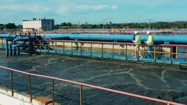 Dos especialistas examinan un clarificador en una instalación de tratamiento de aguas residuales biológicas. Concepto de gestión del agua. — Vídeo de stock