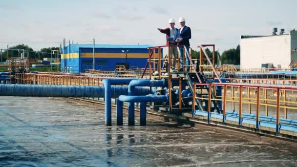 Empresarios hablando en el puente en una instalación de limpieza de aguas residuales — Vídeo de stock