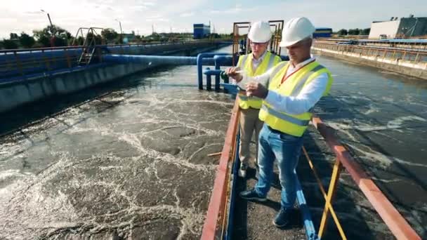 Operatorzy ścieków pobierający próbkę wody ze zbiornika na ścieki — Wideo stockowe