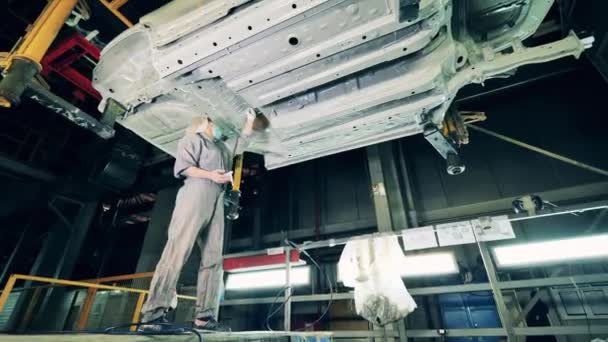 Εργάτης στο εργοστάσιο αυτοκινήτων που βουρτσίζει το σώμα οχημάτων από κάτω — Αρχείο Βίντεο