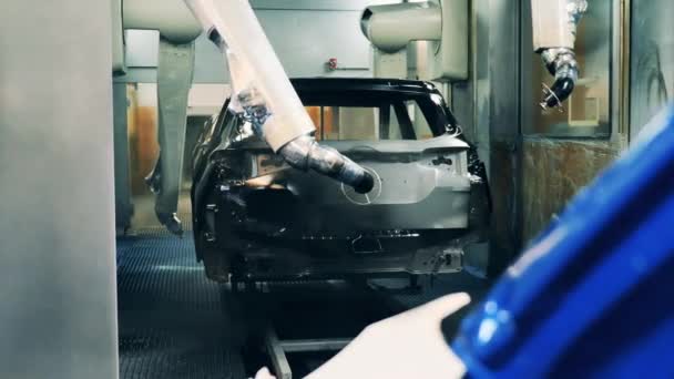 Brazos robóticos pintando un cuerpo de coche negro — Vídeo de stock