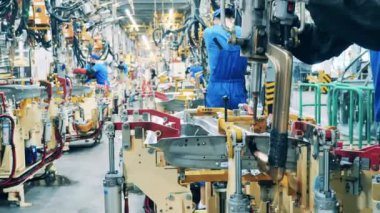 Araba fabrikası işçileri modern bir makine kullanarak araba parçalarını kaynatıyorlar.