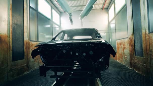 Robotik silah spreyi araba imalat tesisinde bir aracı siyaha boyuyor. — Stok video