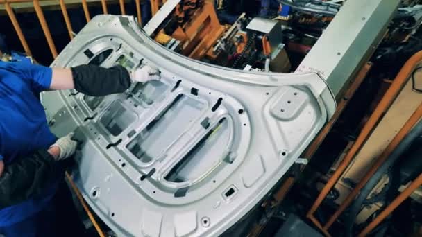 Μηχανικός αυτοκινήτων που συναρμολογεί μια κουκούλα αυτοκινήτου σε ένα εργοστάσιο παραγωγής αυτοκινήτων — Αρχείο Βίντεο