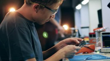 Görevli bir cep telefonunu tamir etmeye çalışıyor.