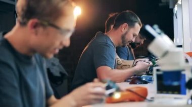Erkek mühendisler lehimleme aletlerini tamir ediyor.