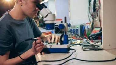 Görevli mikroskop altında bir mikro devreyi tamir ediyor.