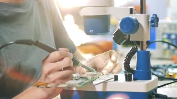 Inżynier lutuje mikroobwód pod mikroskopem. — Wideo stockowe